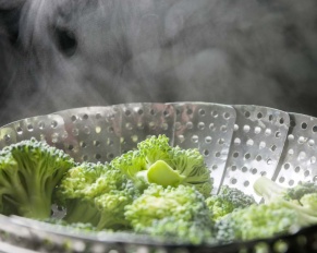 Freshly steamed green broccoli in skimmer pot with steam