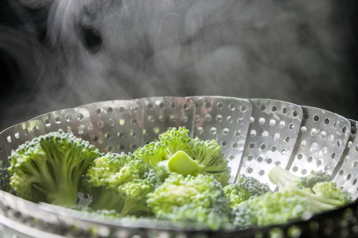 Freshly steamed green broccoli in skimmer pot with steam